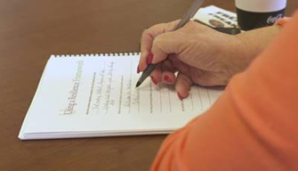 close-up of a woman's hand writing on a piece of paper