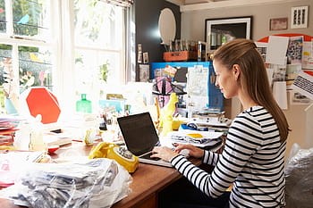 Woman working from home, seated at desk with laptop
